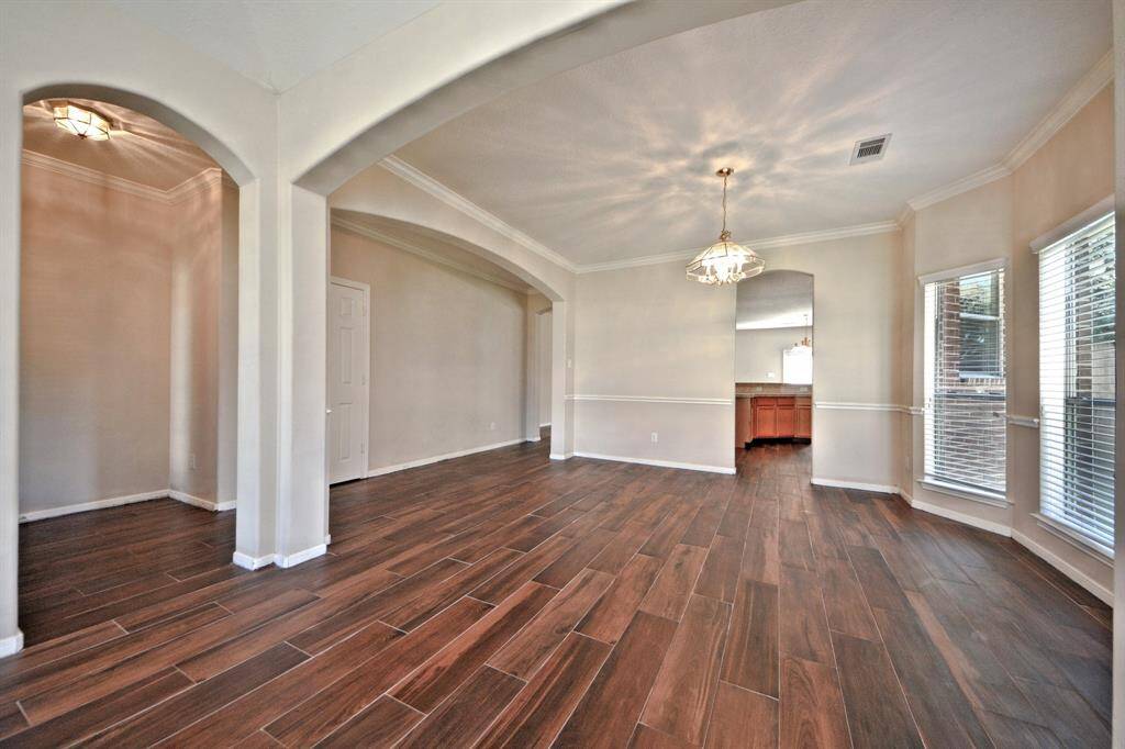The formal dining room connects directly to the gourmet kitchen, making serving and entertaining seamless. Chair railing adds a touch of classic detail, and the hallway leads to more of the home’s functional spaces.