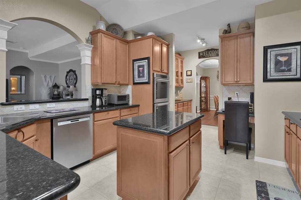 The kitchen has an island and granite counter tops.  There is an abundance of cabinets and counter space with a built-in desk area. The appliances are stainless with double ovens.