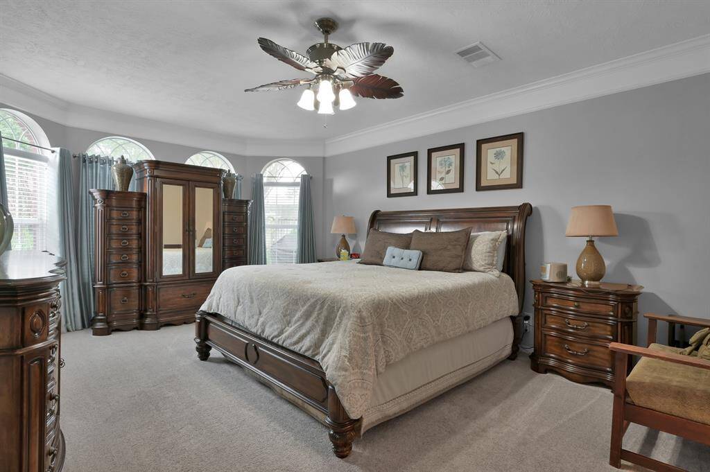 The primary suite is located on the main level of the home.  The crown molding and arched windows continue in the private bedroom.