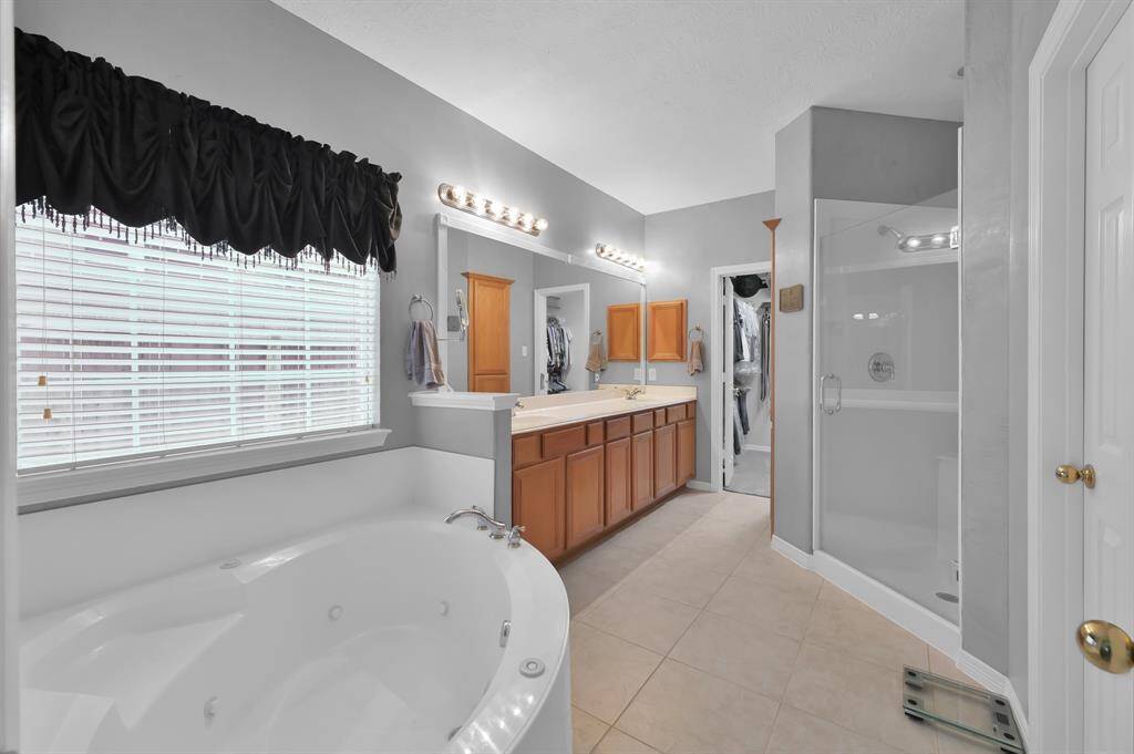 The primary bathroom has a separate shower and large jetted, garden tub.  The vanity has two sinks and a medicine cabinet.  There is a large walk-in closet.