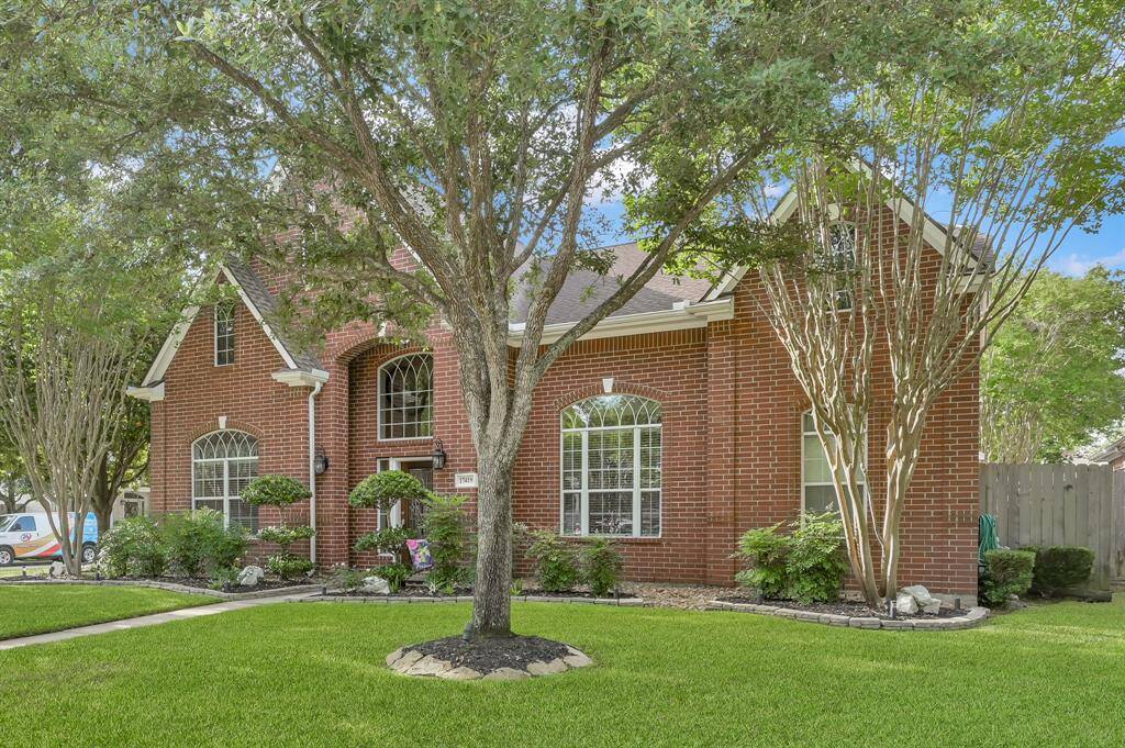 The home has stately red brick and sits on a wooded lot.