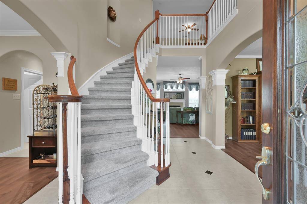 As you enter the home, there is a two-story entry way and a curved staircase. The entry flooring is tile with diamond accents and there is an art niche on the stairway wall.