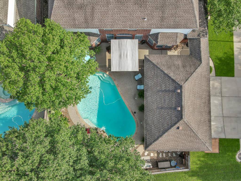 This view shows the pool, covered pergola and three car garage.