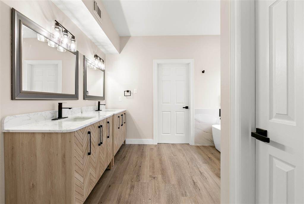 This bathroom features stylish double vanities for plenty of space and storage complemented by updated light fixtures and large framed mirrors.
