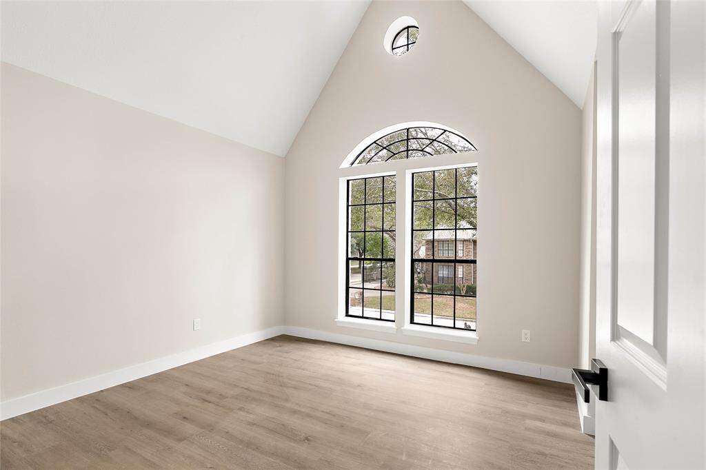 This upstairs bedroom features a high vaulted ceiling and a large arched window to bring the outdoors in.