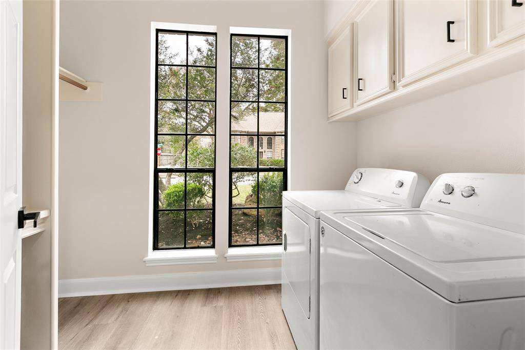 Functional laundry room including washer and dryer and ample cabinet storage.