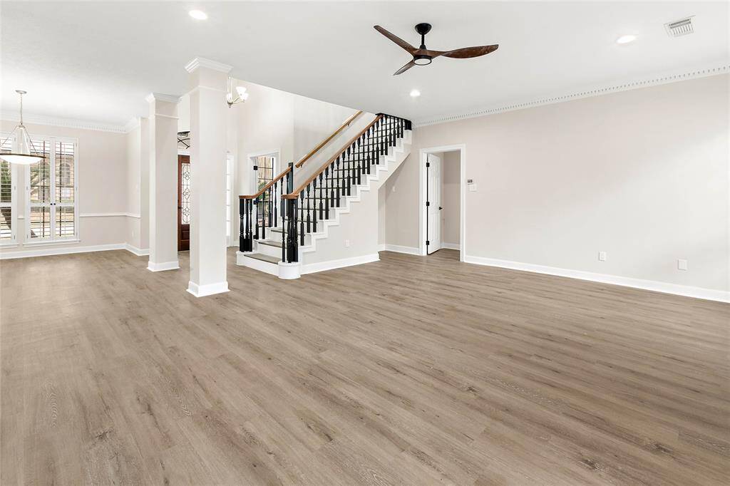 The family room features elegant flooring and an abundance of natural light from large windows. The ceiling fan adds a modern touch to the inviting space.