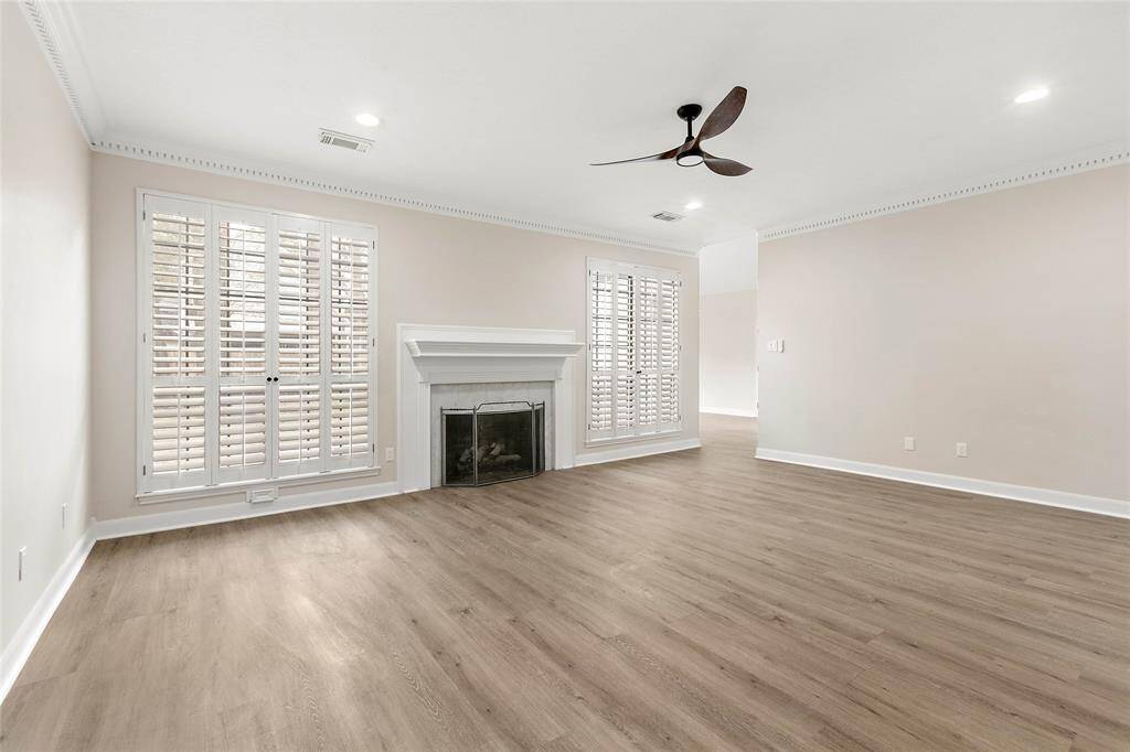 A view into the family room showcases a cozy fireplace and large windows with Plantation shutters.