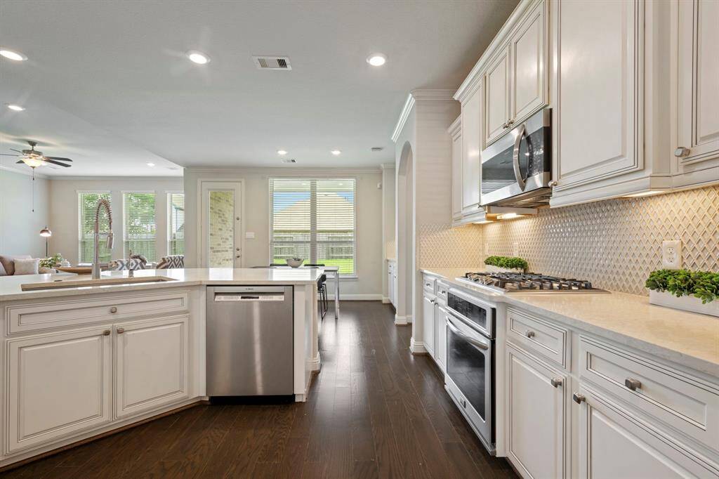 This modern kitchen features elegant white cabinetry, a spacious island with seating and stainless steel appliances.