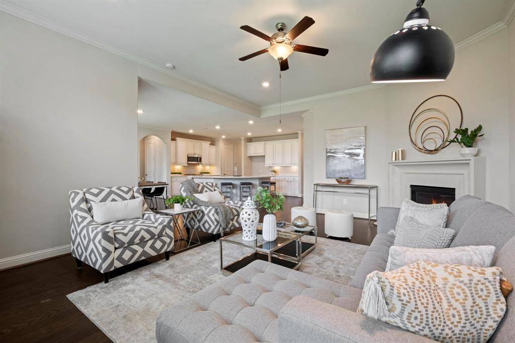 This inviting living room features a cozy fireplace, and large windows that provide ample natural light seamlessly connecting to a contemporary kitchen with sleek cabinetry and a breakfast bar.