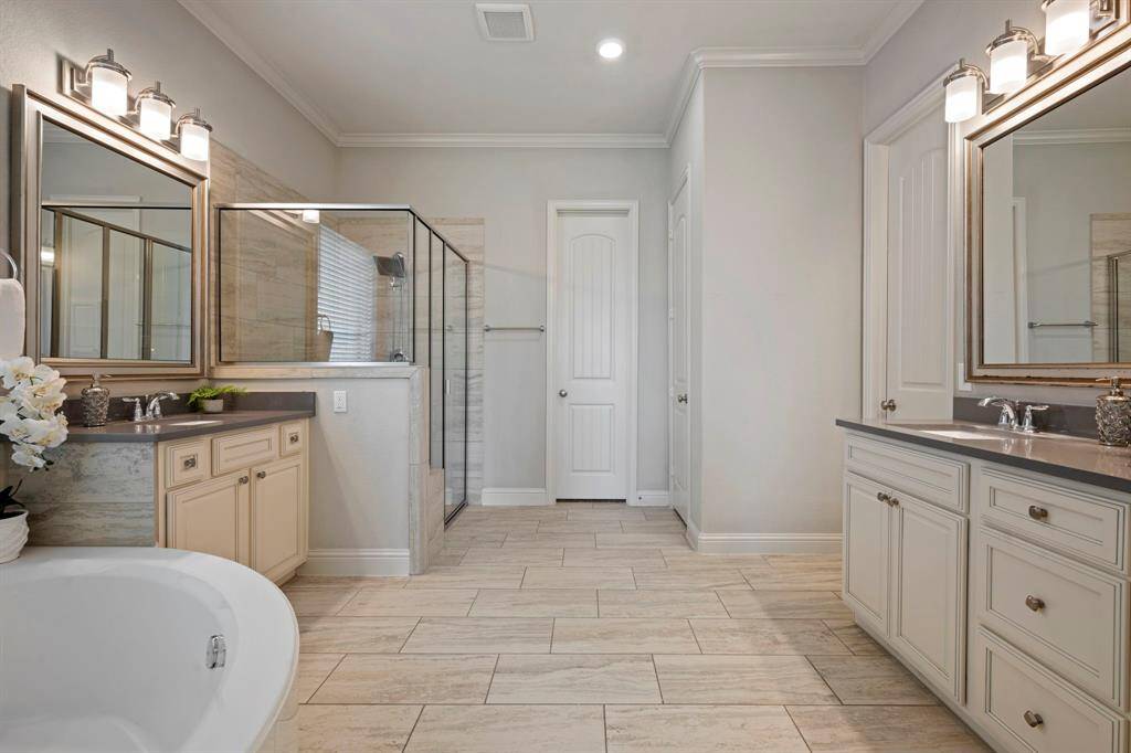 Spacious primary bathroom with dual sinks, a large soaking tub, and a glass-enclosed shower.