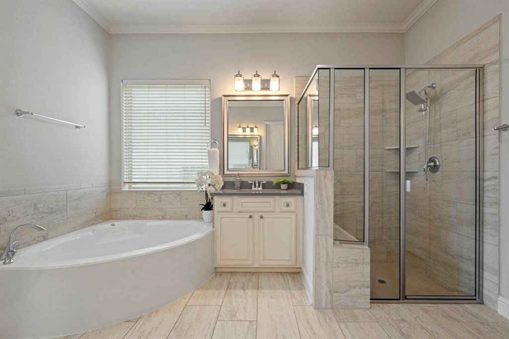 Spacious primary bathroom with dual sinks, a large soaking tub, and a glass-enclosed shower.
