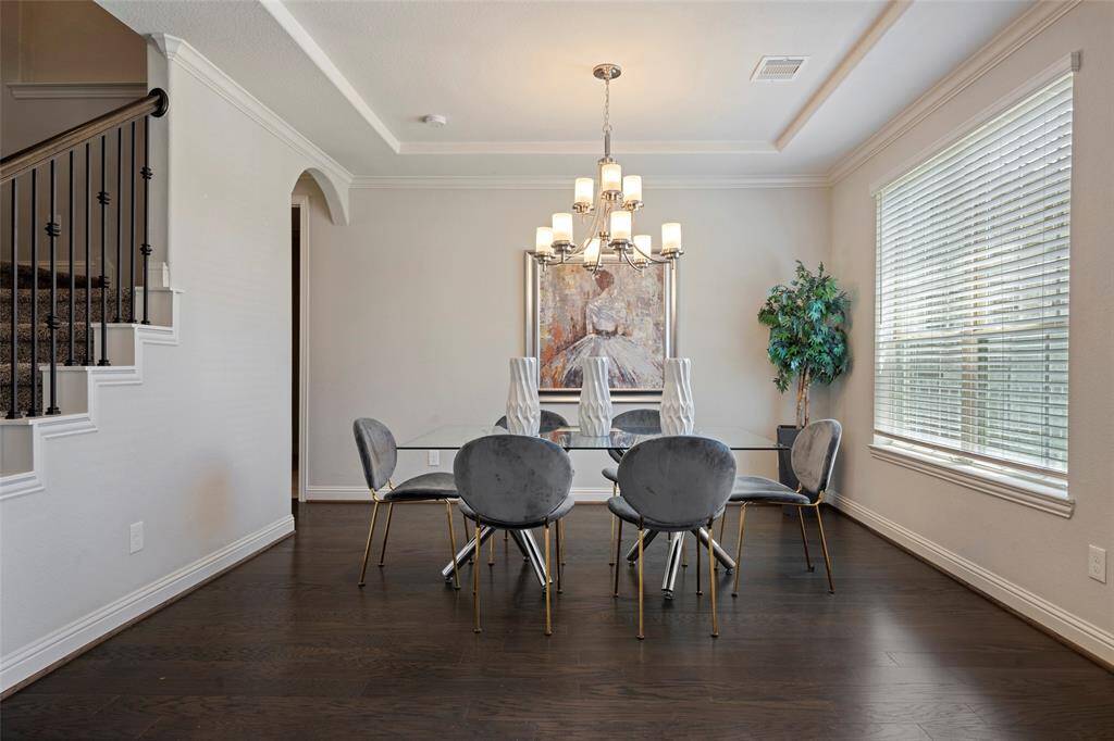 Formal dinning area with large windows providing ample natural light. A staircase with elegant railing is visible to the side.
