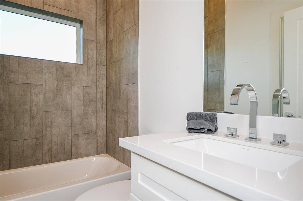 The downstairs bathroom has fantastic tile in the shower/tub  that goes perfectly with the contemporary look of the hardware and the modern sink.
