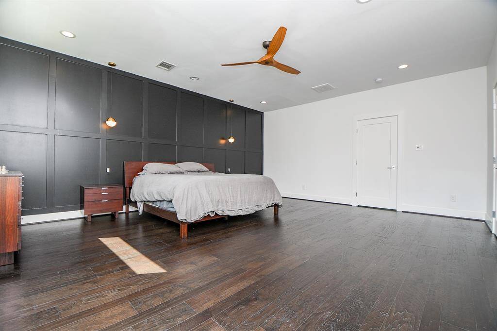 Another view of the enormous master bedroom with a custom-made accent wall and contemporary suspended lights.