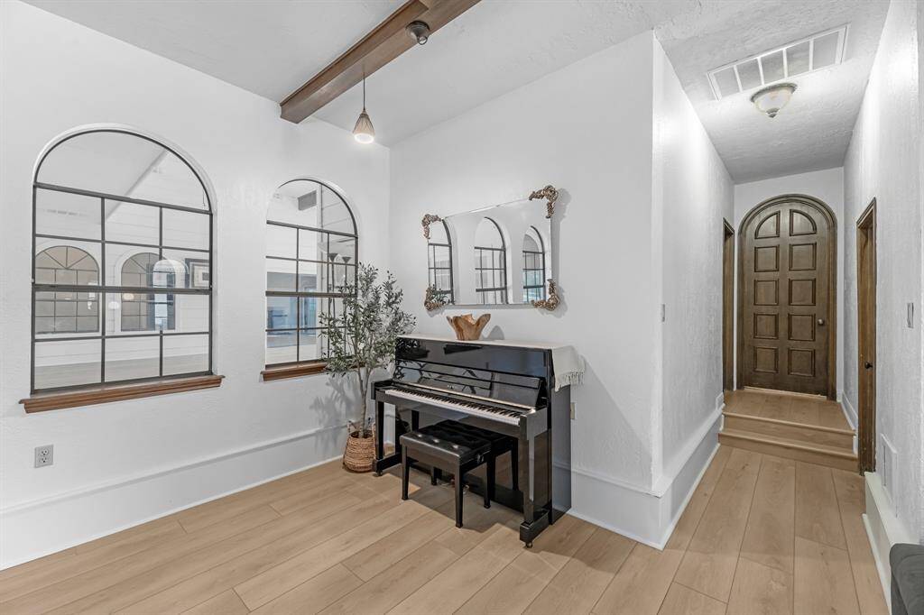 Arched windows and a classic piano nook. Doorway that enters the primary suite.