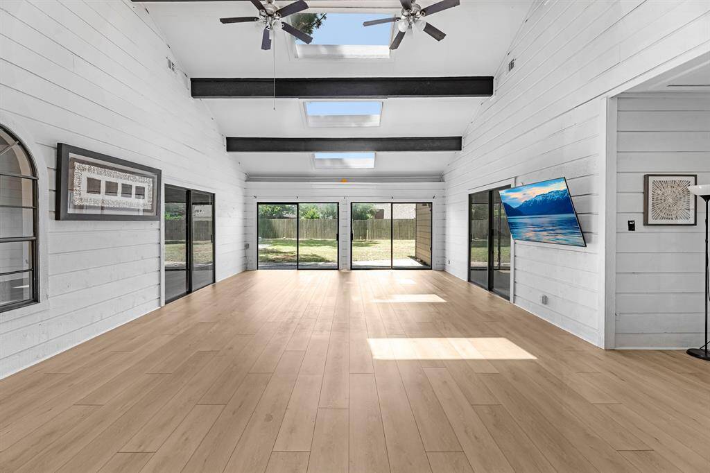 Massive sunroom with skylights, beams, and backyard views.