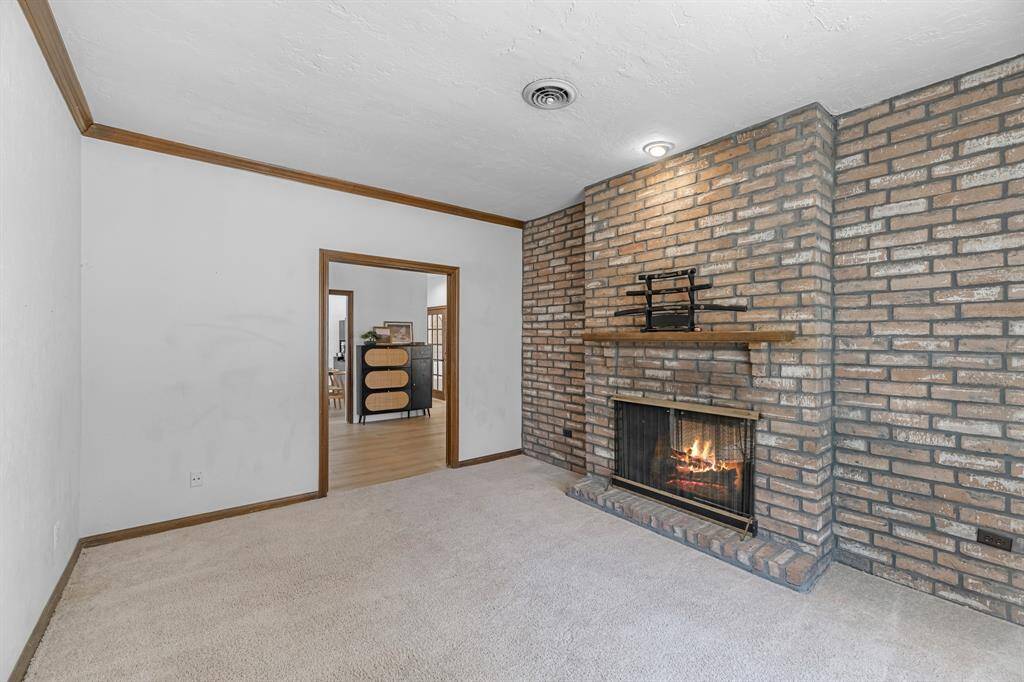 Enjoy a quiet workspace or reading nook beside a charming double-sided brick fireplace that also warms the living room. Solid wood trim and plush carpeting create a comfortable and inviting atmosphere.