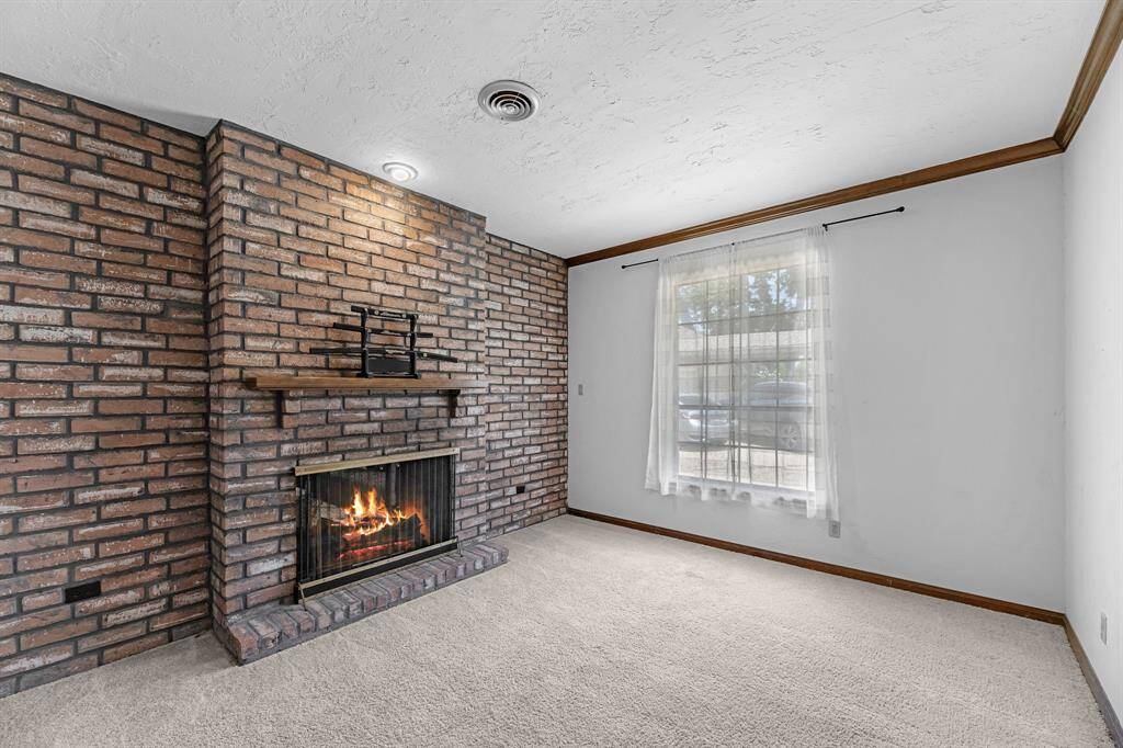 Enjoy a quiet workspace or reading nook beside a charming double-sided brick fireplace that also warms the living room. Solid wood trim and plush carpeting create a comfortable and inviting atmosphere.