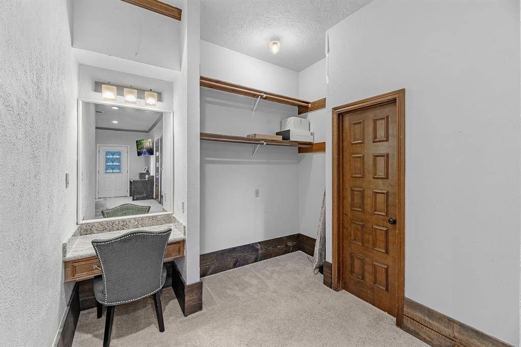 Private vanity space with granite countertop and a spacious walk-in closet.