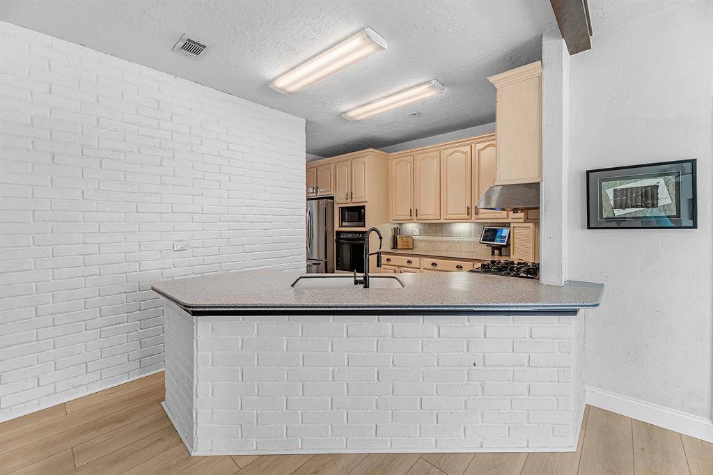 Open kitchen with a breakfast bar and white brick accent wall.