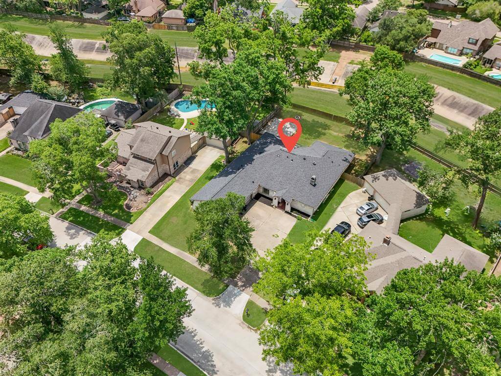 Welcome to your dream home, perfectly situated with a spacious backyard and mature trees offering privacy and shade. This aerial view showcases the home’s curb appeal, large driveway, and close proximity to neighborhood greenbelts and walking trails. A serene setting paired with convenience—this is the ideal spot to call home