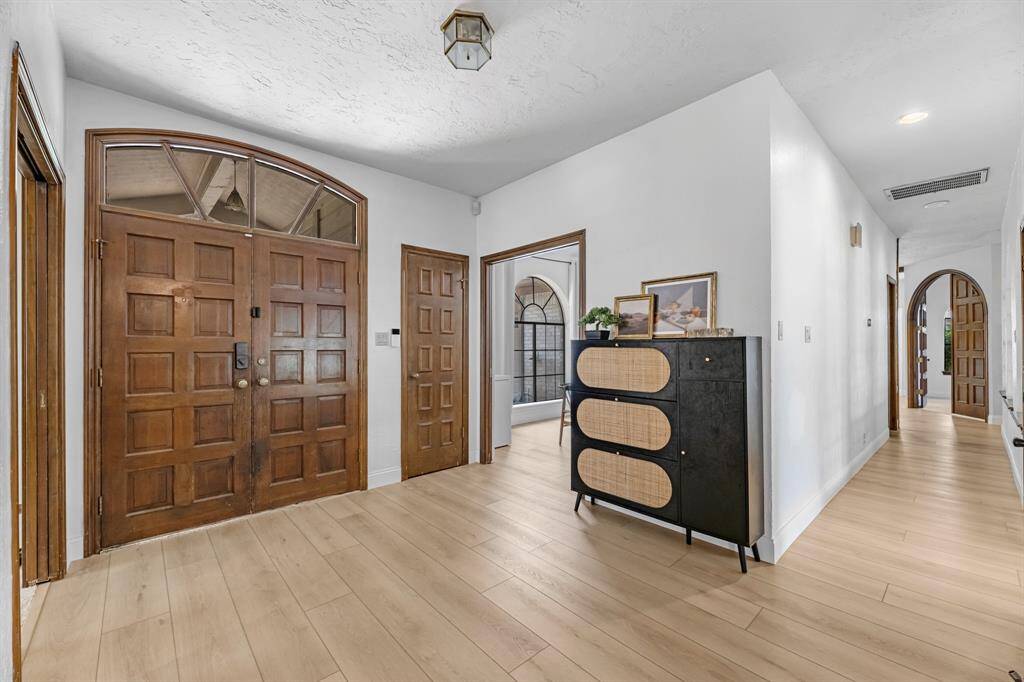 Make a statement from the moment you walk in with this impressive entryway boasting solid wood double doors, sleek new flooring, and arched details. The wide hallway and updated lighting create a warm welcome while providing access to key areas of the home in a layout that’s both functional and inviting.