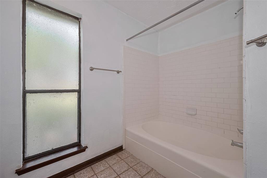A tiled tub/shower combo is paired with a frosted window that adds privacy without sacrificing natural light.
