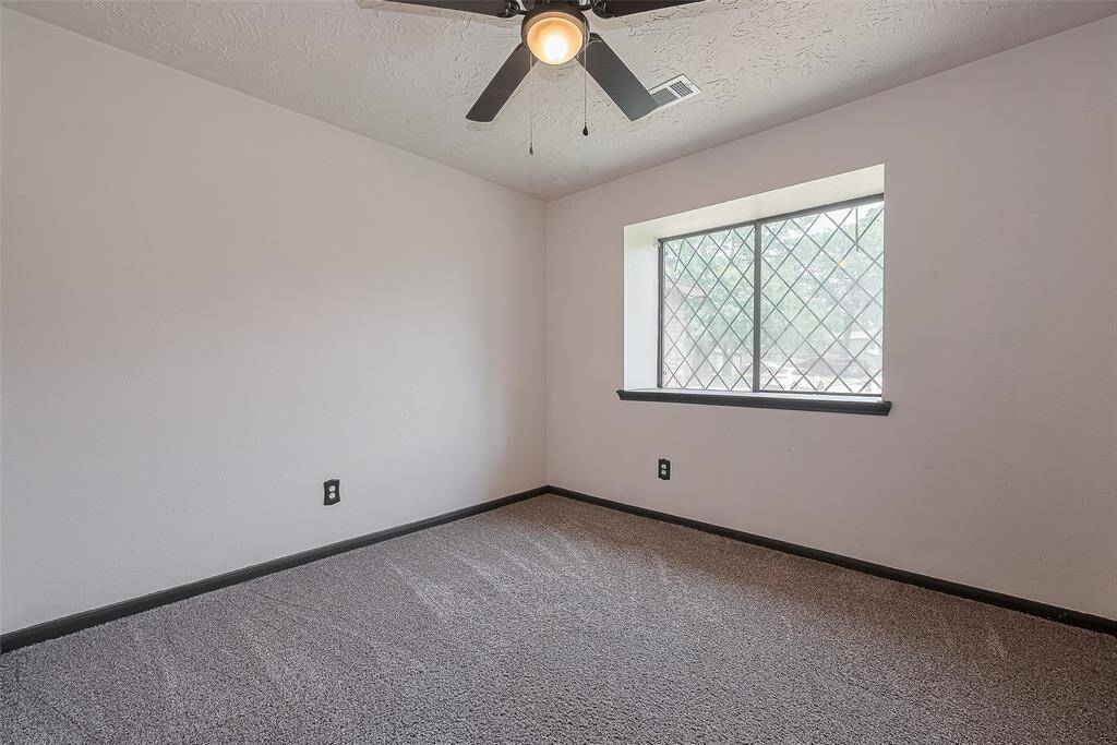 This secondary bedroom offers a cozy retreat with a modern ceiling fan and a charming window with diamond-pane glass.
