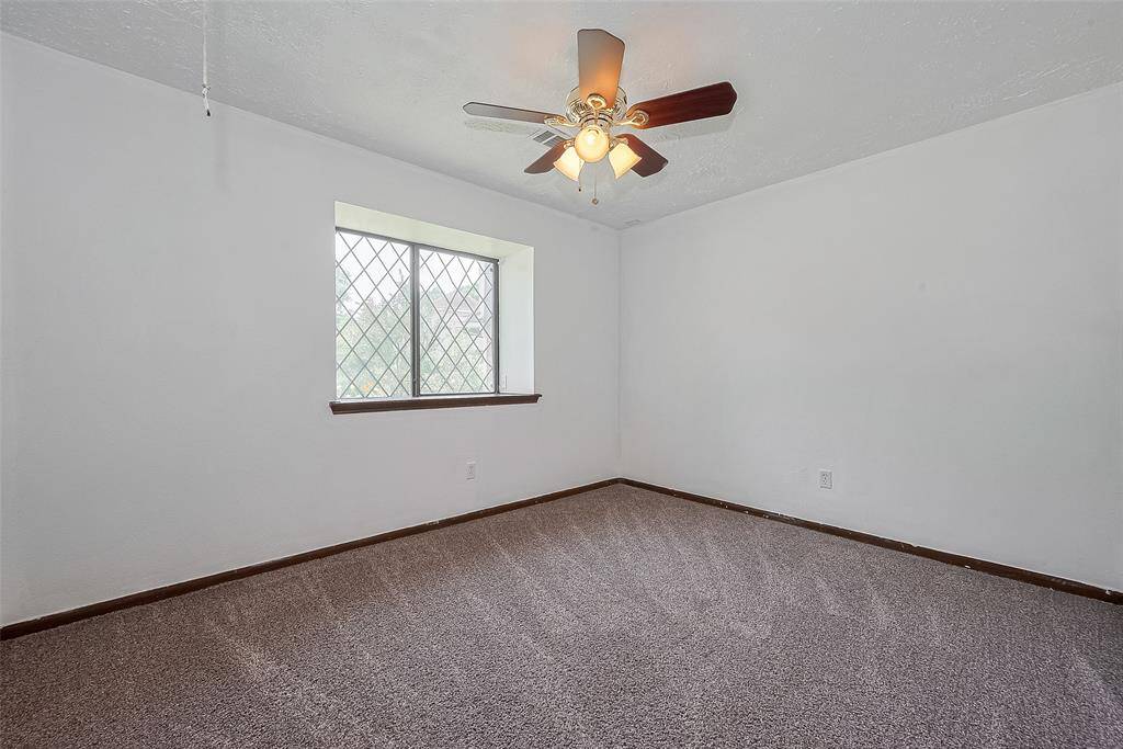 Another generously sized bedroom features soft carpet underfoot and a large window that fills the space with natural light.