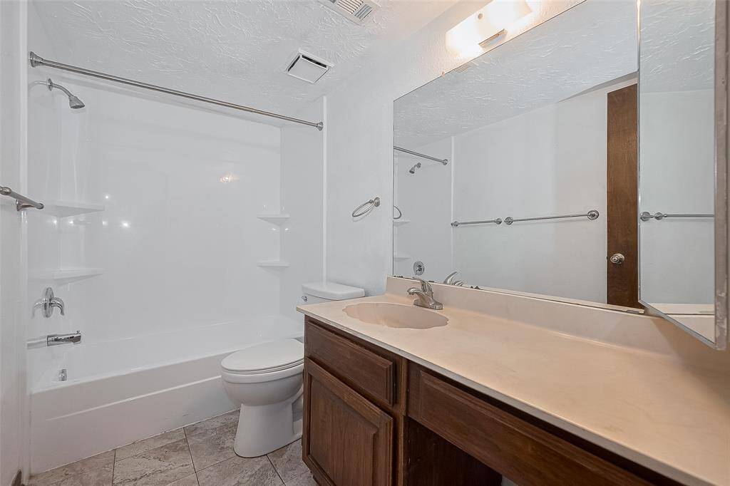 The secondary bathroom features a full shower/tub combo with built-in shelving and updated tile flooring.