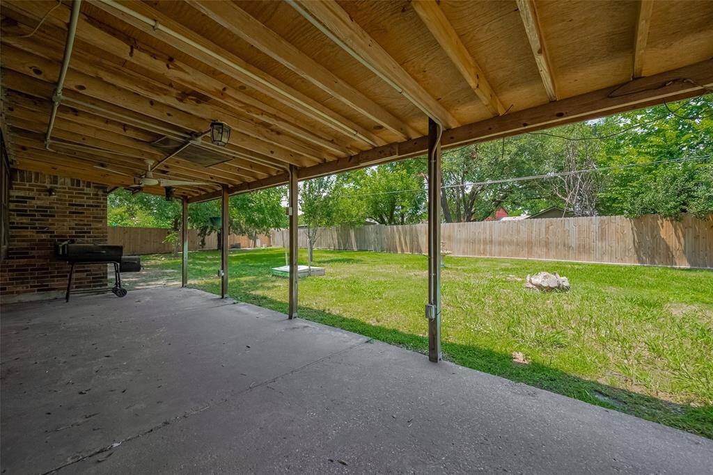 A wide covered patio stretches the length of the home, providing a shaded retreat for grilling or relaxing outdoors.