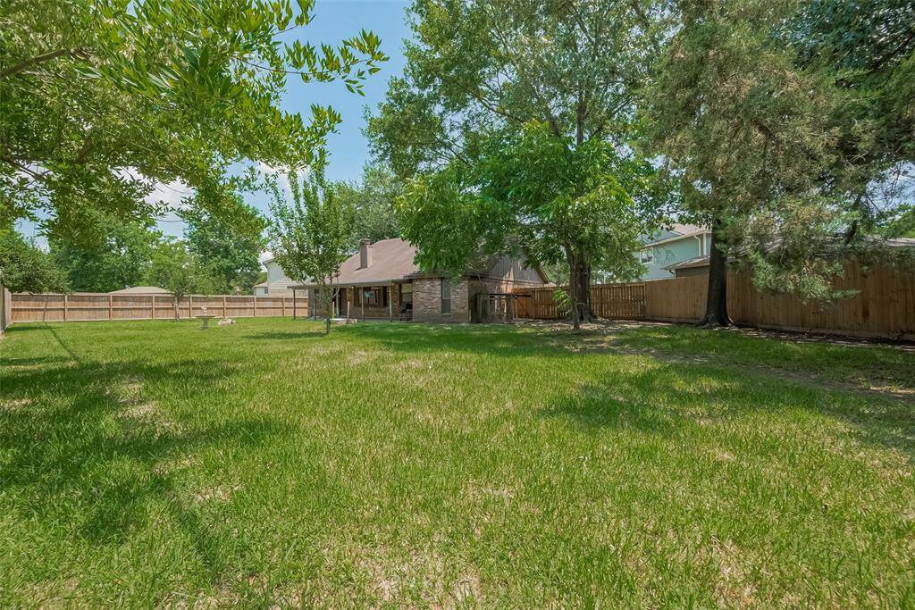 The backyard is a dream for gardeners or outdoor lovers, offering mature trees and open grassy space.