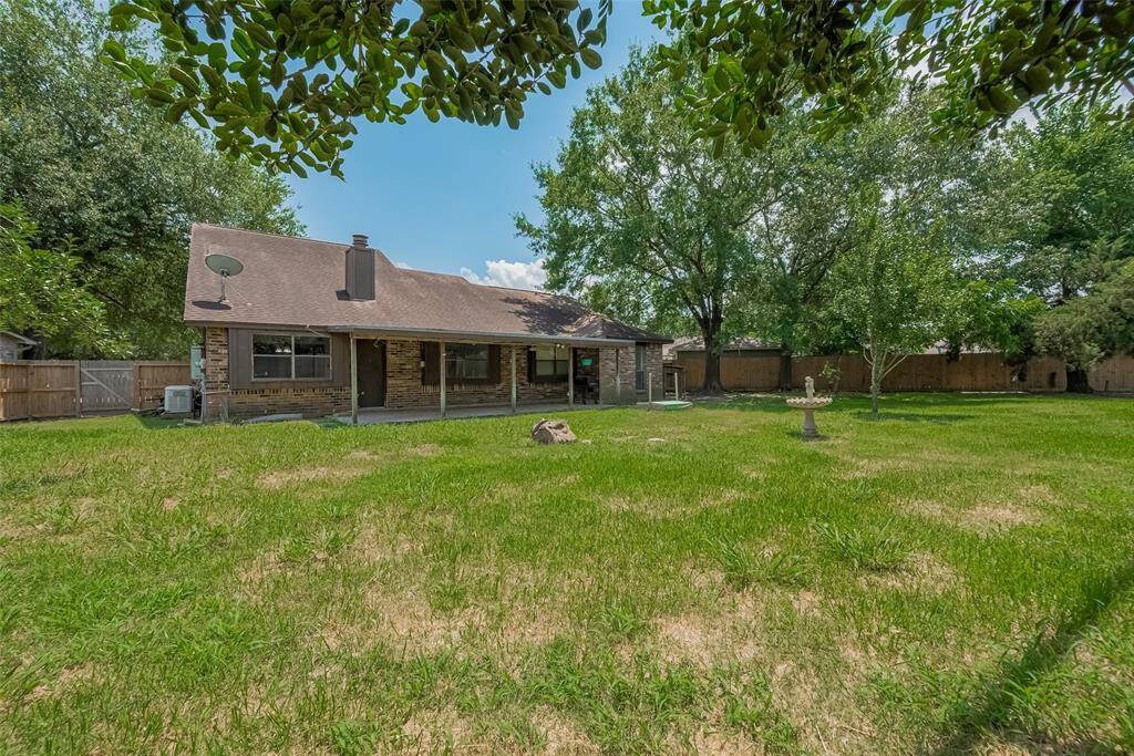 A wide view of the backyard shows the full scope of this private outdoor retreat, with trees lining the back fence and open space for play or landscaping.