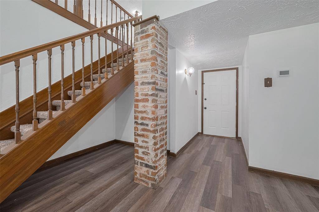 Step inside to find a wide foyer with wood-look vinyl flooring and a stylish exposed brick column.
