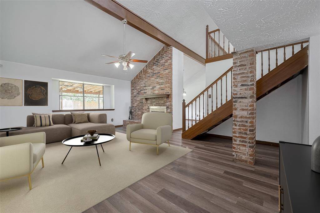 A soaring ceiling with exposed wood beams and a central ceiling fan enhances the sense of volume and architectural charm.