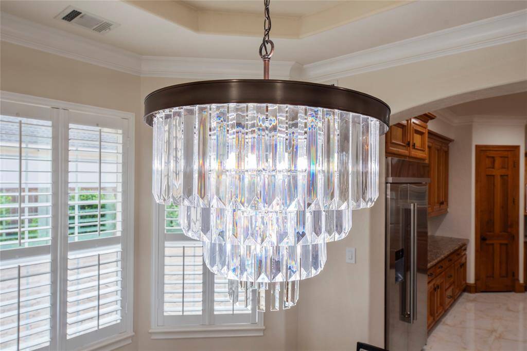 An opulent, statement-making designer chandelier gracefully illuminates the breakfast table, serving as a stunning centerpiece that elevates the entire space.