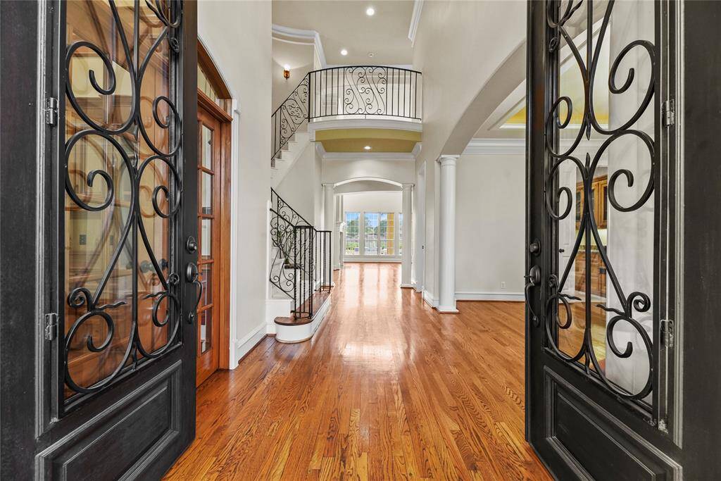 Step through the grand double leaded-glass doors into an exquisite foyer adorned with gleaming hardwood floors and a sweeping staircase. Elegant columns frame the entrance to the formal dining room, setting a tone of timeless sophistication and refined grandeur.
