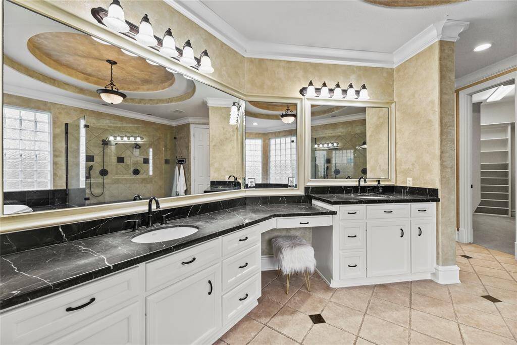 The primary bathroom boasts elegant double vanities beneath a stunning ceiling, complemented by exquisite tiled floors that add both texture and sophistication to this spa-like sanctuary.