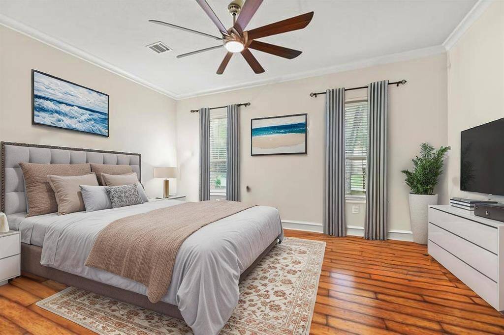 The second bedroom on the main level is bathed in abundant natural light, highlighting the rich wood floors that lend warmth and timeless elegance to the serene retreat.