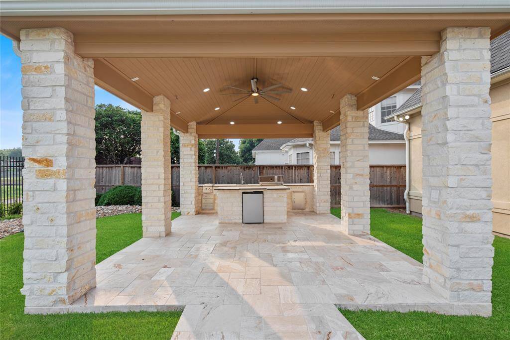 The luxurious, standalone covered patio—artfully crafted in brick and stone—features a fully equipped outdoor kitchen and ample space for an elegant alfresco dining experience. Perfectly positioned beside the sparkling pool, it offers a serene and sophisticated setting for open-air entertaining at its finest.