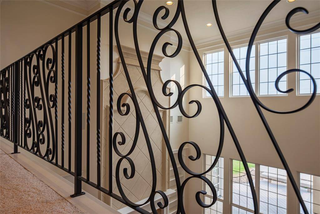 Designer wrought-iron spindles and ornate gates grace the upper-level overlook, adding a touch of artistry and architectural elegance that enhances the home's overall grandeur.