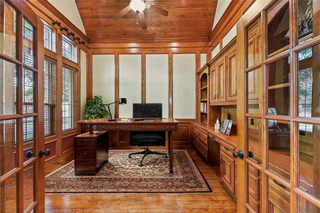 Just off the grand entryway lies your private home office, richly appointed with exquisite custom-built wood cabinetry and floor-to-ceiling bookshelves. Shuttered windows allow for soft, natural light, while warm hardwood floors complete the space with timeless elegance.