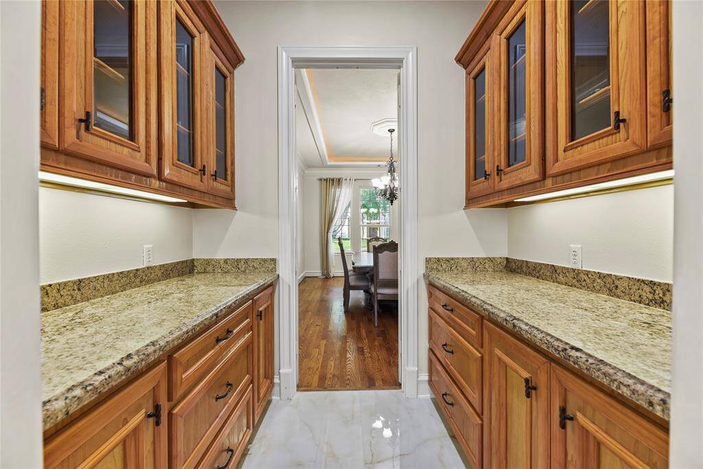 The butler’s pantry is a refined extension of the dining experience, featuring gleaming granite countertops and elegant glass-front cabinetry—perfect for displaying your finest china and stemware with style and grace.