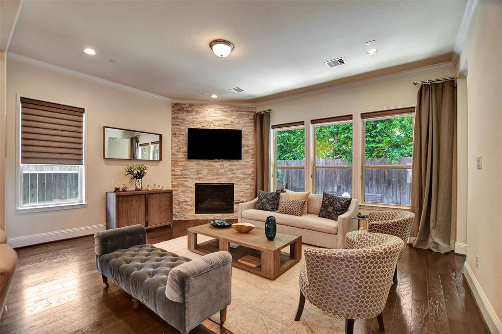 This spacious living area features a coffered ceiling with recessed lighting and large windows for natural light. All windows have high-end window coverings providing privacy, helping to keep the house cool, or just simply for decoration.