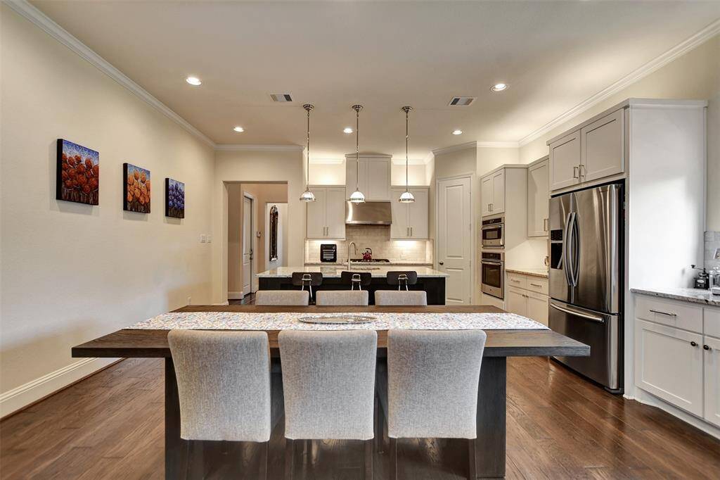 This modern kitchen features sleek white cabinetry, a large island with seating, elegant lighting with ample natural light, perfect for entertaining.