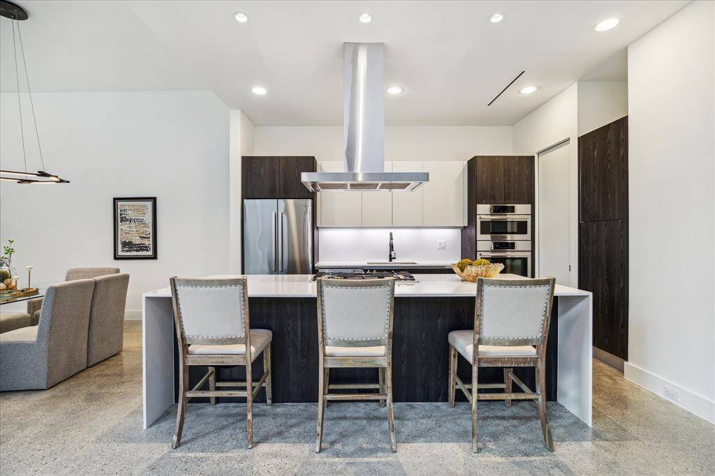 This minimalist dream kitchen hides all the right things—including a spacious walk-in pantry discreetly tucked behind a pocket door. Clean lines, high end finishes, and designer lighting elevate everyday living.