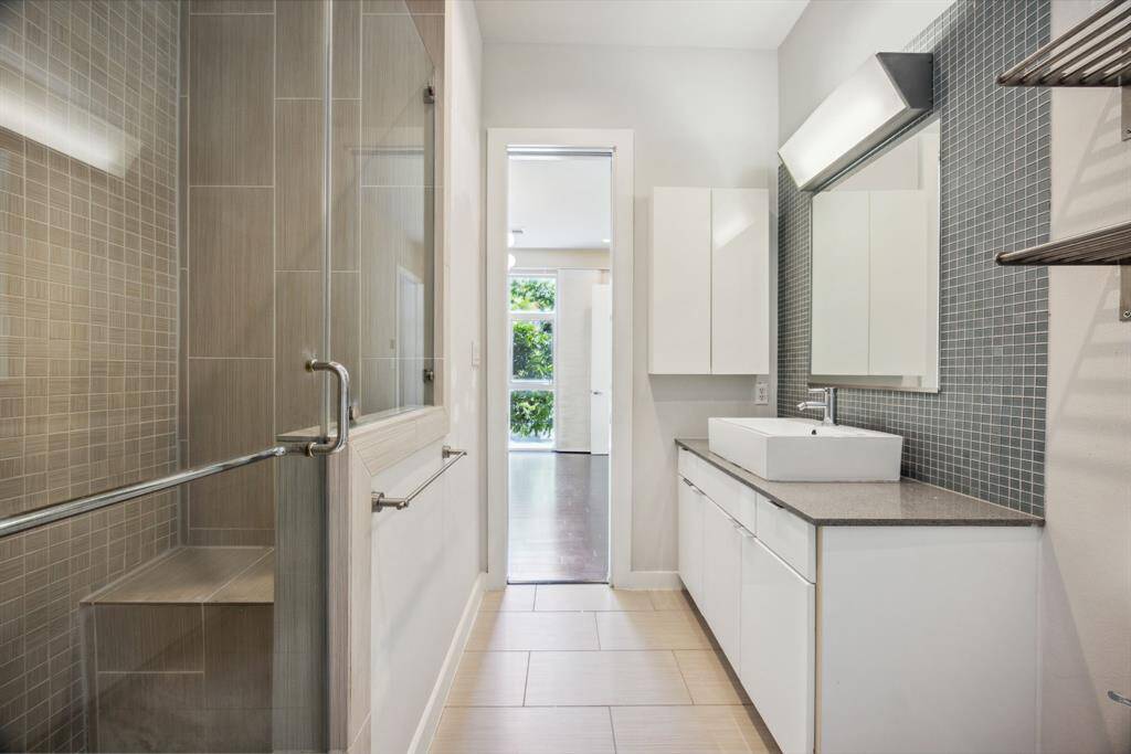 The ensuite bath features a spacious walk in shower, quartz counters, plenty storage, and decorative tile finishes.