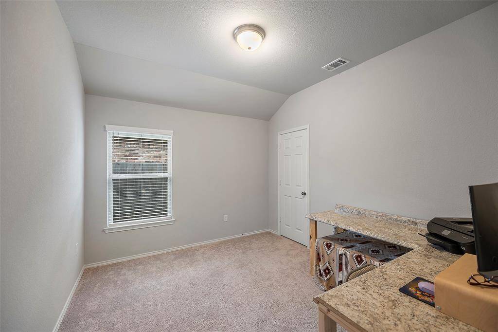 Bedroom 2- neutral walls and carpet flooring, featuring a single window with blinds and a built-in desk space. Perfect for a home office or guest bedroom.