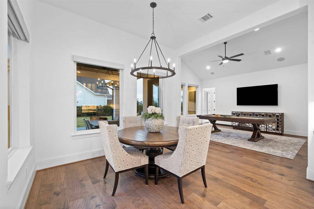 Nestled beside tall windows, the casual dining nook bridges the kitchen and game room, balancing natural light with everyday comfort.